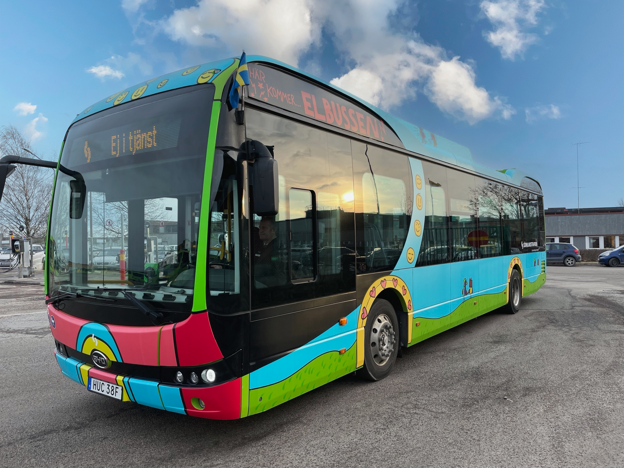 Bilden visar den vinnande bussen från senaste upplagan av tävlingen. Det är en färgglad buss med hjärtan och smiley-ikoner. Den har också texten "Här kommer elbussen".